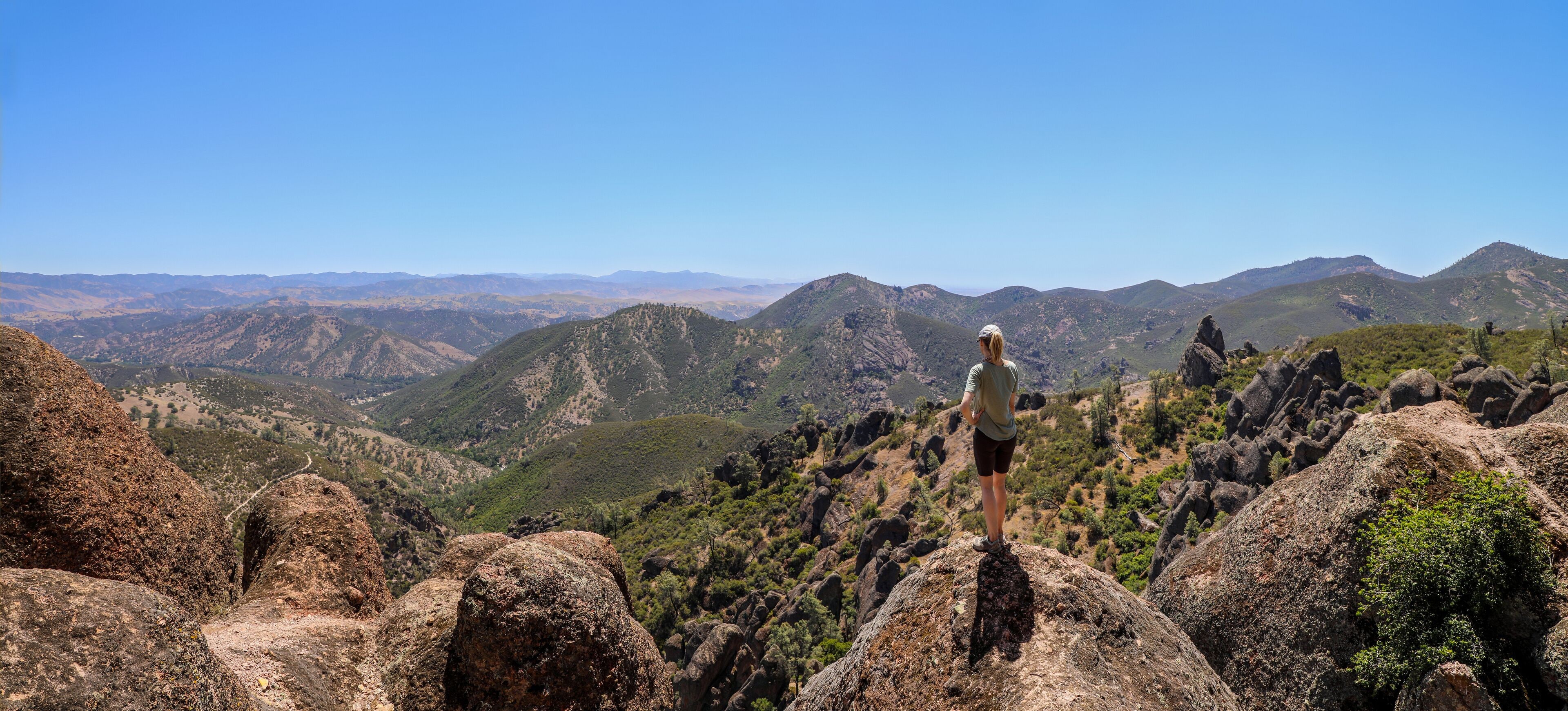 Woman standing on rock overlooking  the beautiful landscape of Pinnacles National Park in California