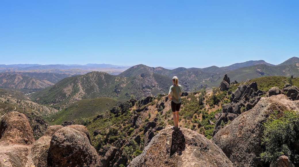 Woman standing on rock overlooking the beautiful landscape of Pinnacles National Park in California