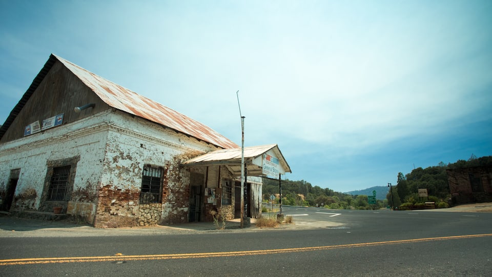 An old, weathered building with a rusted roof and a small storefront.