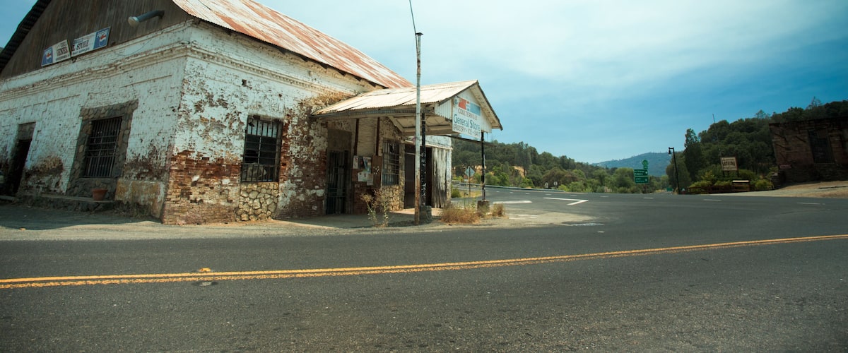 An old, weathered building with a rusted roof and a small storefront.