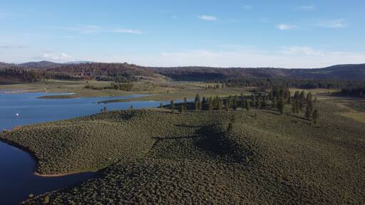 Frenchman Lake reservoir in California west shore hills and trees drone high POV photo