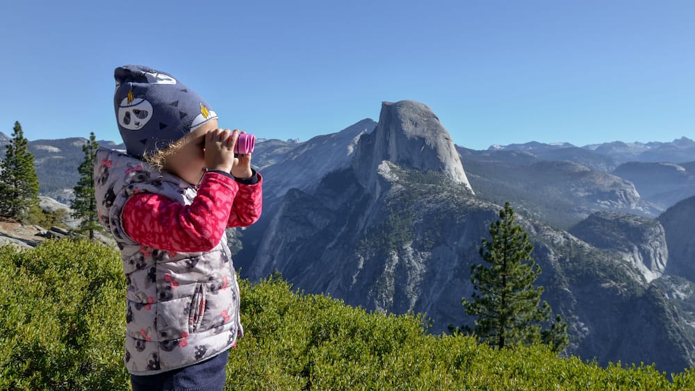 A person taking a photo of a mountain landscape with a prominent rock formation.