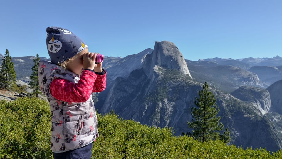 A person taking a photo of a mountain landscape with a prominent rock formation.