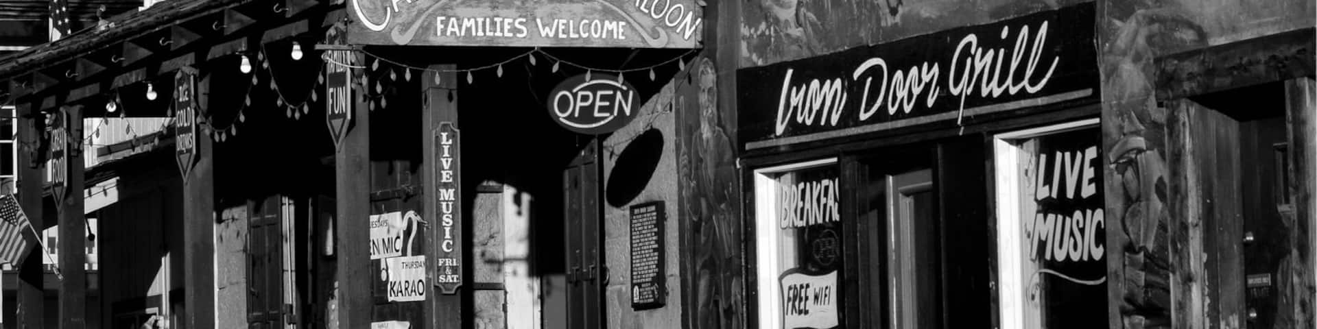A black and white photo of a historic building with signs for 'Iron Door Saloon' and 'California Oldest Saloon'.