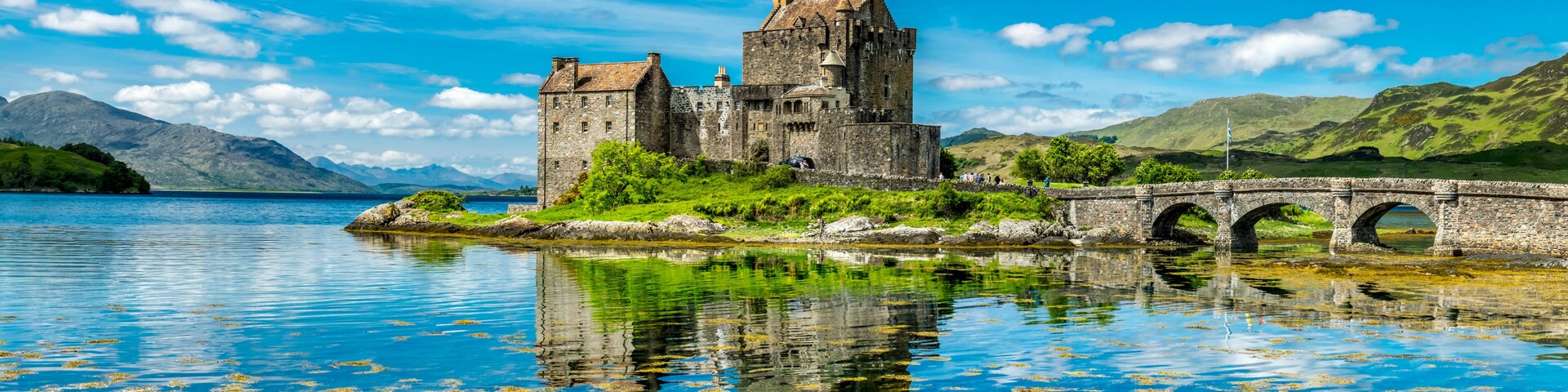 A historic castle by a lake with a stone bridge.