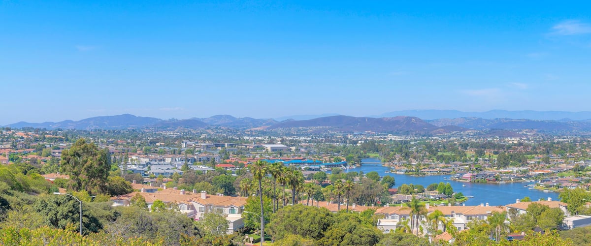 A coastal town with a lake, surrounded by mountains and greenery.