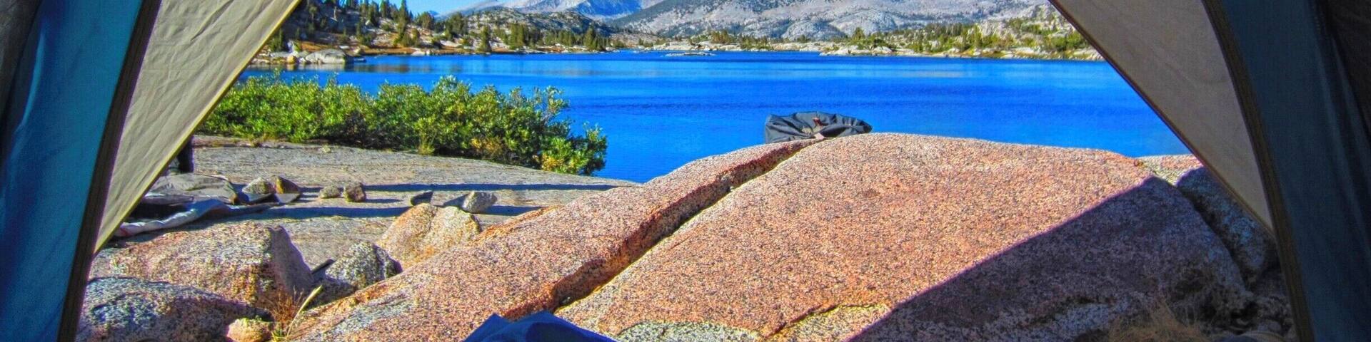 A tent with a view of a lake and mountains.