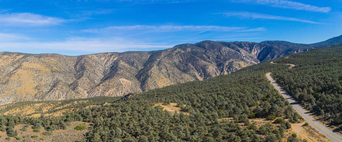 A winding road through a mountainous area with dense forests and rocky terrain.