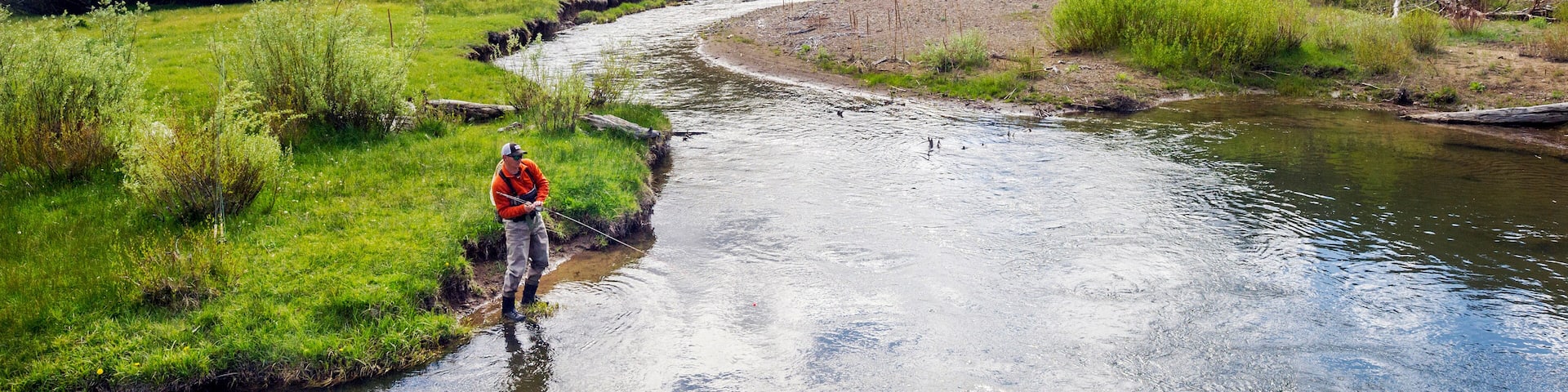 A man, Brendan Burnside, catches a fish fly fishing in Pleasant Valley Creek in Markleeville, California.