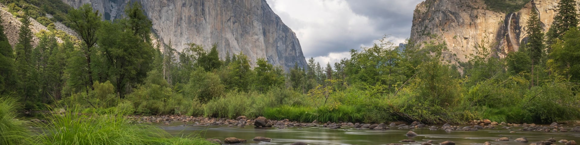 A river with rocks and green vegetation in a mountainous landscape.