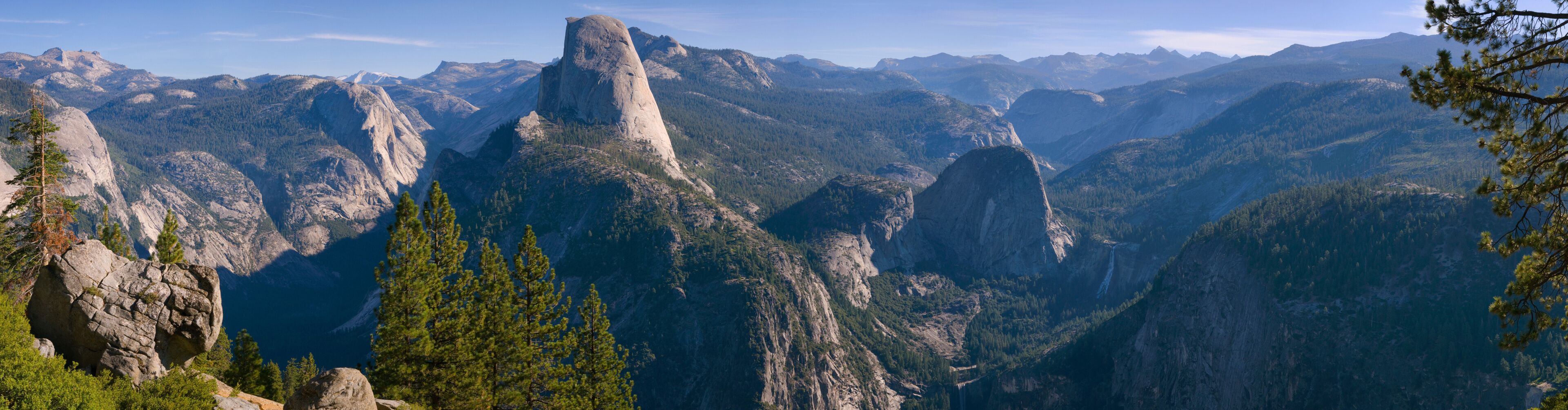 A mountainous landscape with prominent rock formations and dense forests.