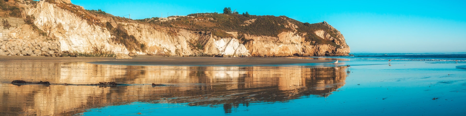 Un paysage cĂŽtier avec des falaises, une plage de sable et une mer calme.
