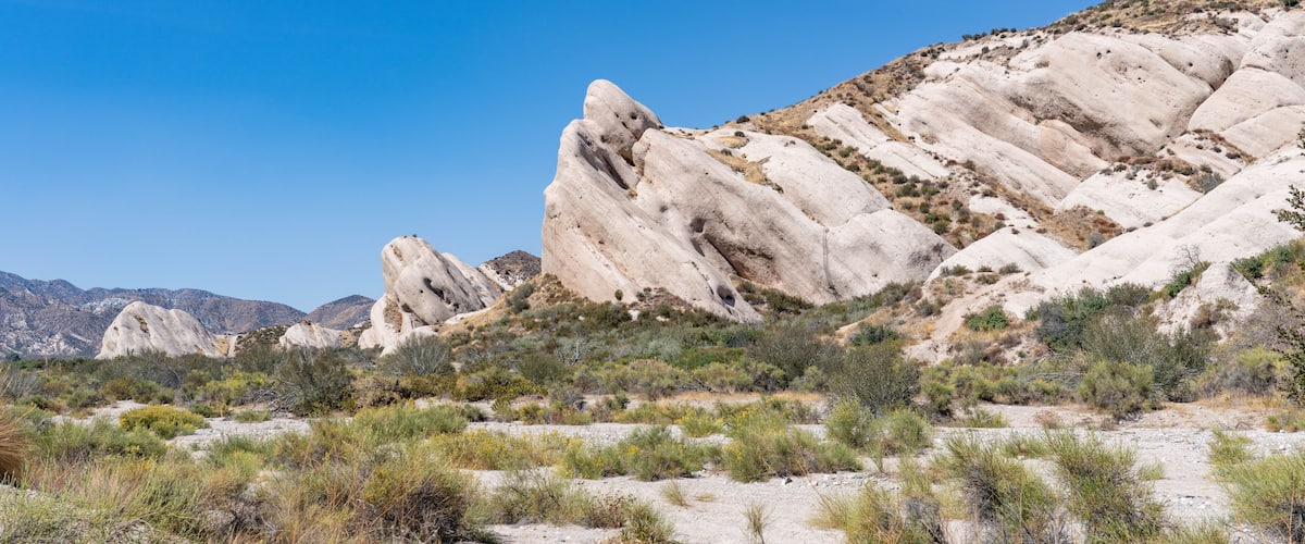 A desert landscape with prominent rock formations and sparse vegetation.