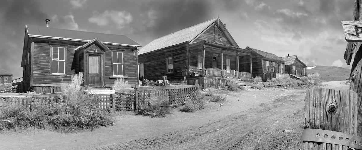 A rustic wooden building with a porch, a dirt road leading to it, and a wooden sign that reads "Prospect St."
