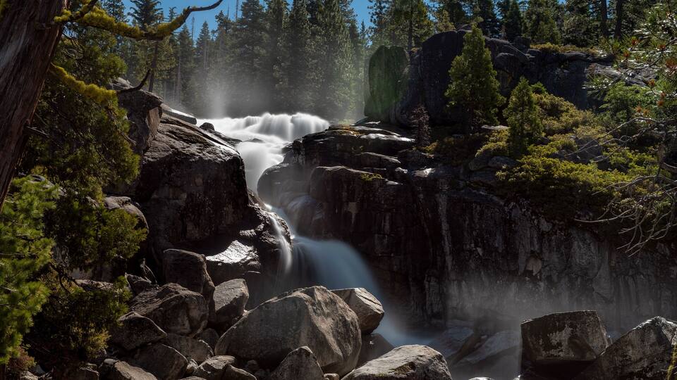 A waterfall cascading over rocks in a forested area.