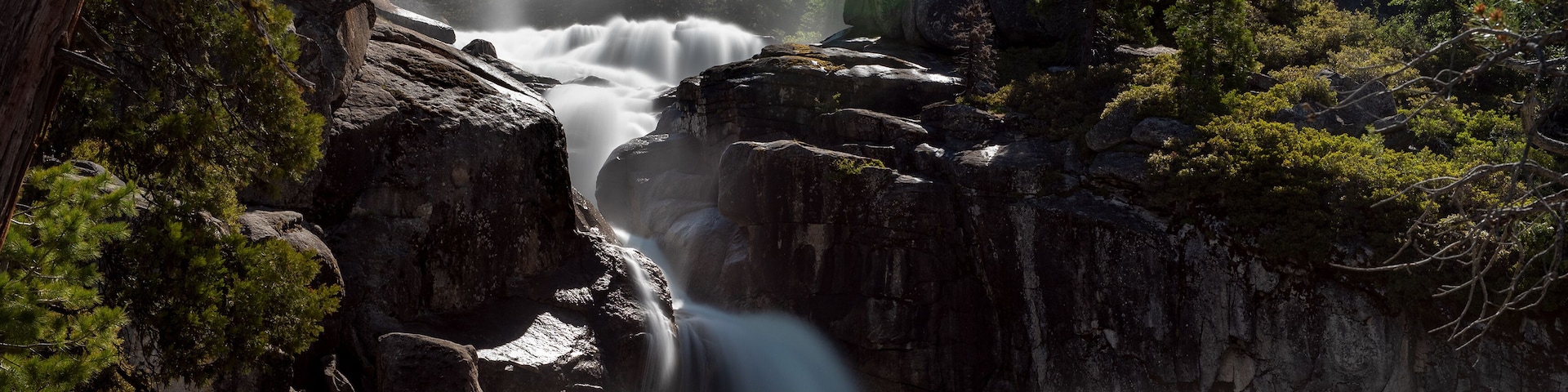 Una cascada fluye sobre rocas en un área boscosa.