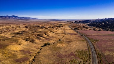 Uma vasta paisagem ondulada com uma estrada sinuosa serpenteando por ela.