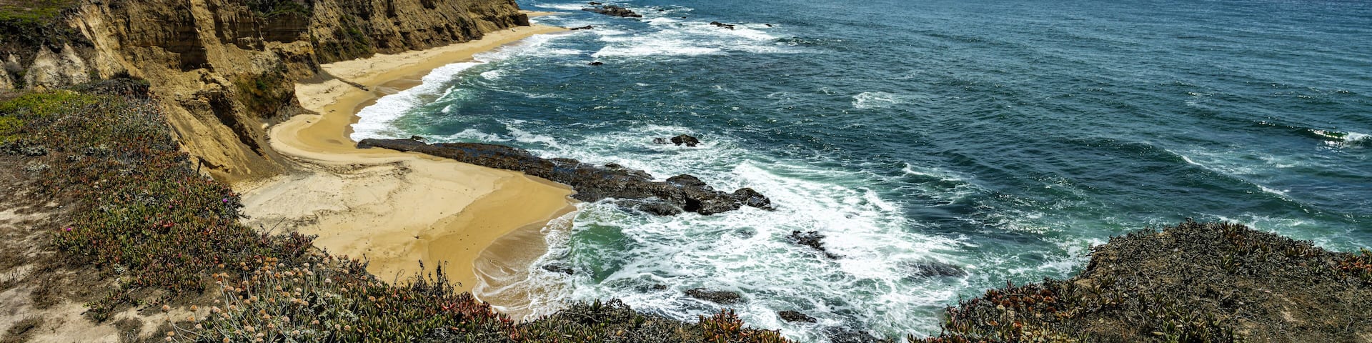 Panorama of the Pacific ocean on sandy Cowell Ranch State beach surrounded by sea cliffs, rocky headlands on sunny day in San Mateo County, California