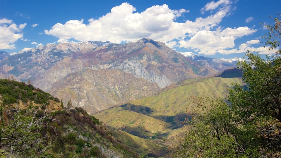 A mountainous landscape with a valley and a range of mountains in the background.