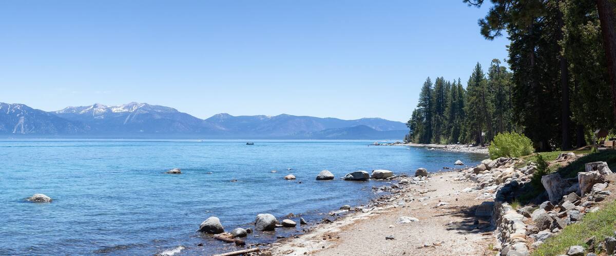 Panoramic View of Rocky Beach and Dock at the Lake surrounded by Mountains and Trees. Summer Season. Sugar Pine Point Beach, Tahoma, California, United States. Sugar Pine Point State Park. Panorama