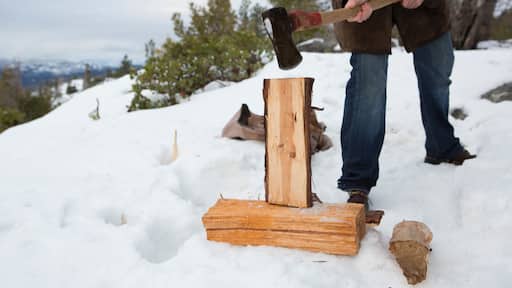 Mid adult man chopping logs on snow covered mountain, Twain Harte, California, USA