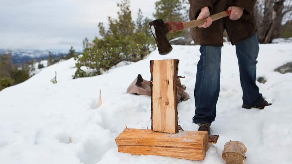A person chopping wood in a snowy outdoor setting.