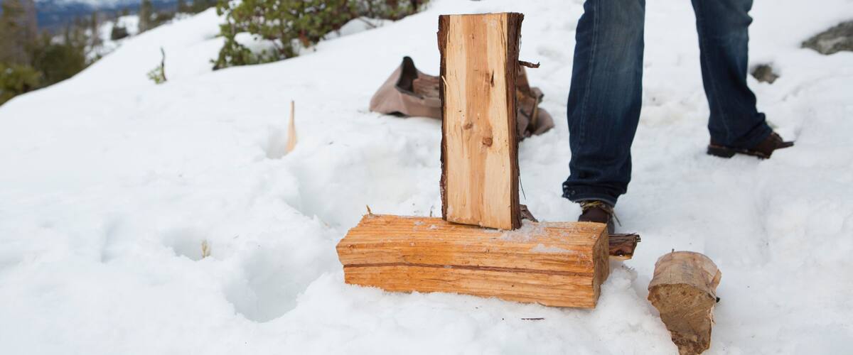 A person chopping wood in a snowy outdoor setting.