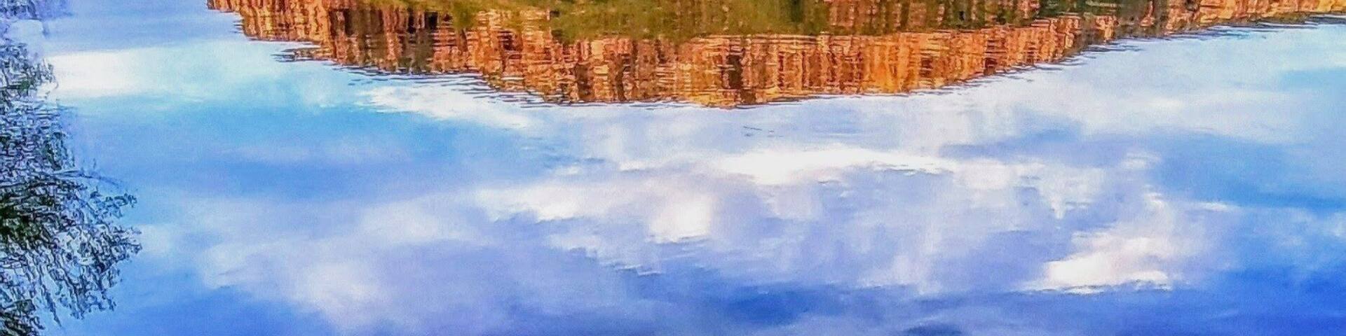 A calm lake with clear water reflecting a mountainous landscape.