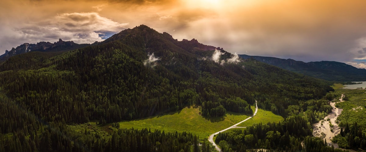 Un valle con un río, rodeado de montañas y bosques densos.