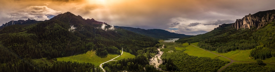A valley with a river, surrounded by mountains and dense forests.