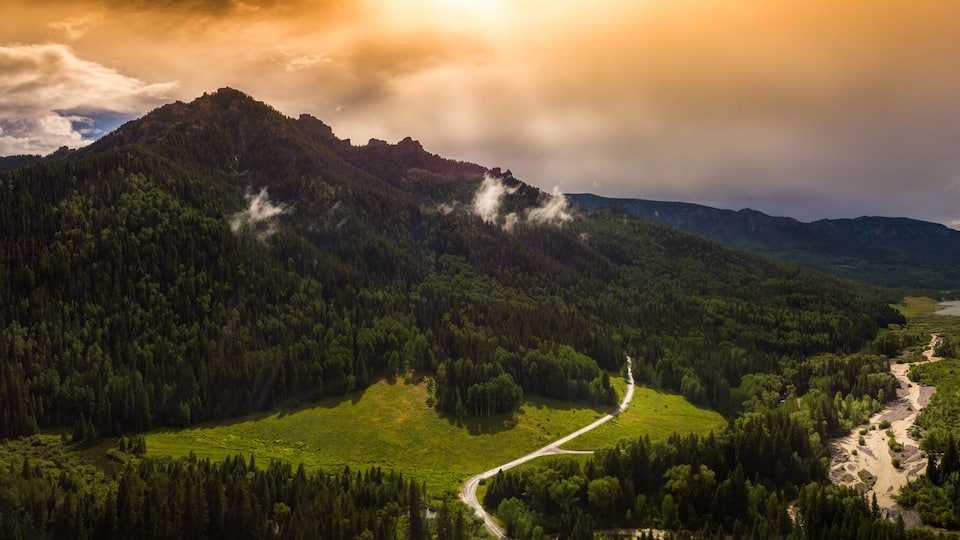 A valley with a river, surrounded by mountains and dense forests.