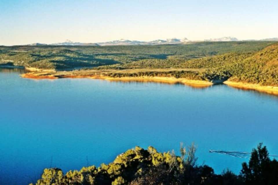 Un grand lac entouré de collines et de montagnes boisées.