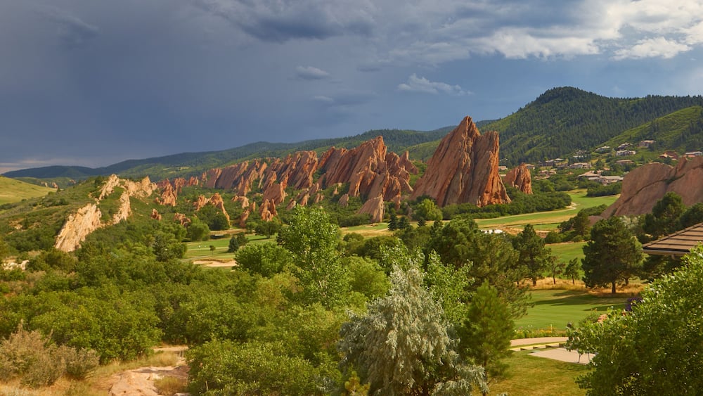 Un paysage caractérisé par des formations rocheuses rouges, des arbres verdoyants et un terrain de golf.