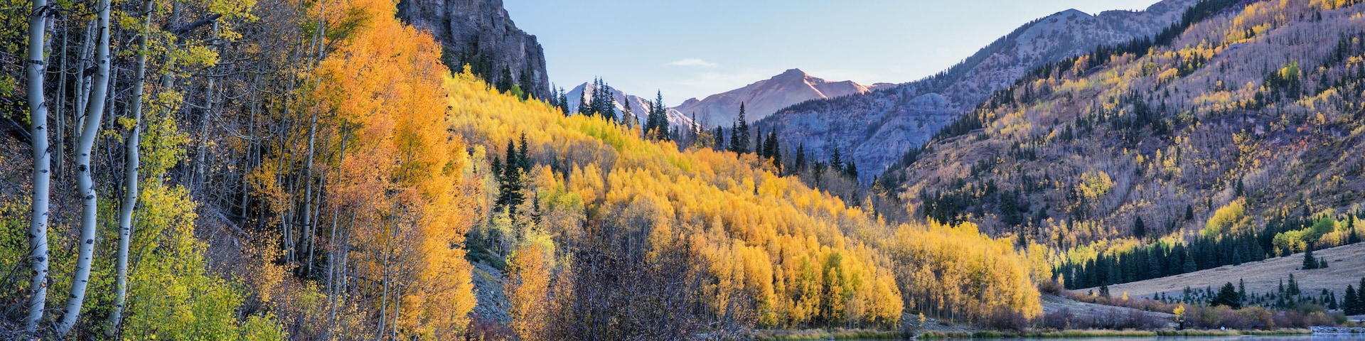 A mountain landscape with autumn foliage, a lake, and a clear sky.
