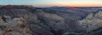 A canyon with layered rock formations and a river at its base.