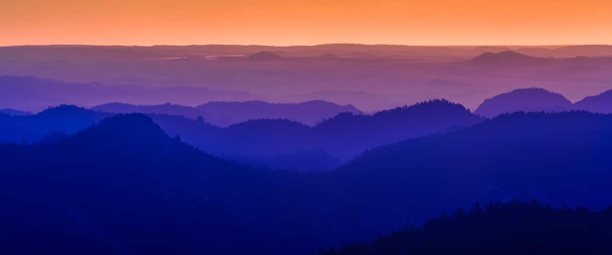A mountain range with a gradient sky at sunrise or sunset.