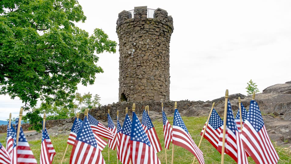 A stone tower with American flags in front.