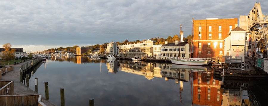 Un río tranquilo con barcos, muelles de madera y edificios a lo largo de la orilla.