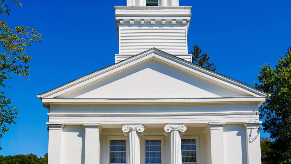 Une église blanche avec un clocher et des portes bleues.