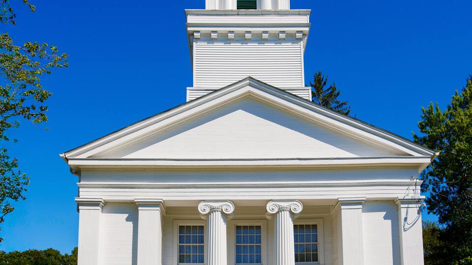 A white church with a bell tower and blue doors.