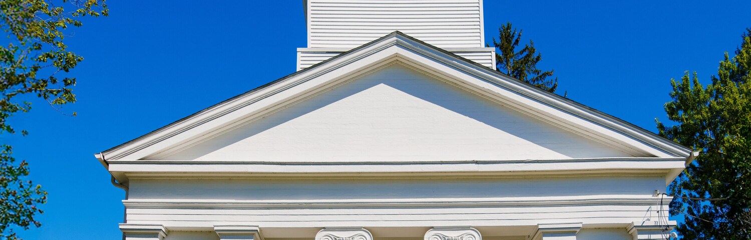 Una iglesia blanca con un campanario y puertas azules.