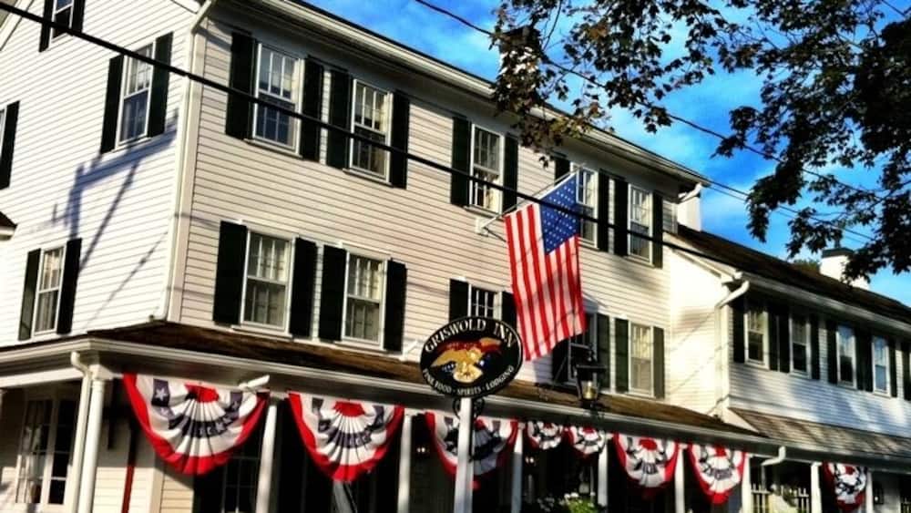 A white building with black shutters, an American flag, and a sign that reads "CHILD'S INN."