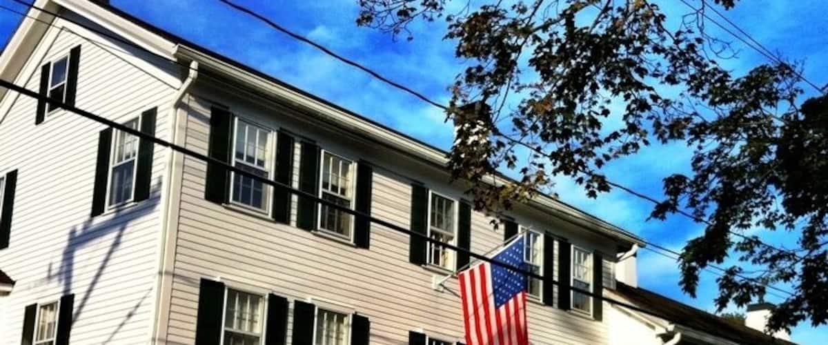Um edifício branco com persianas pretas, uma bandeira americana e uma placa que diz 'CHILD'S INN'.