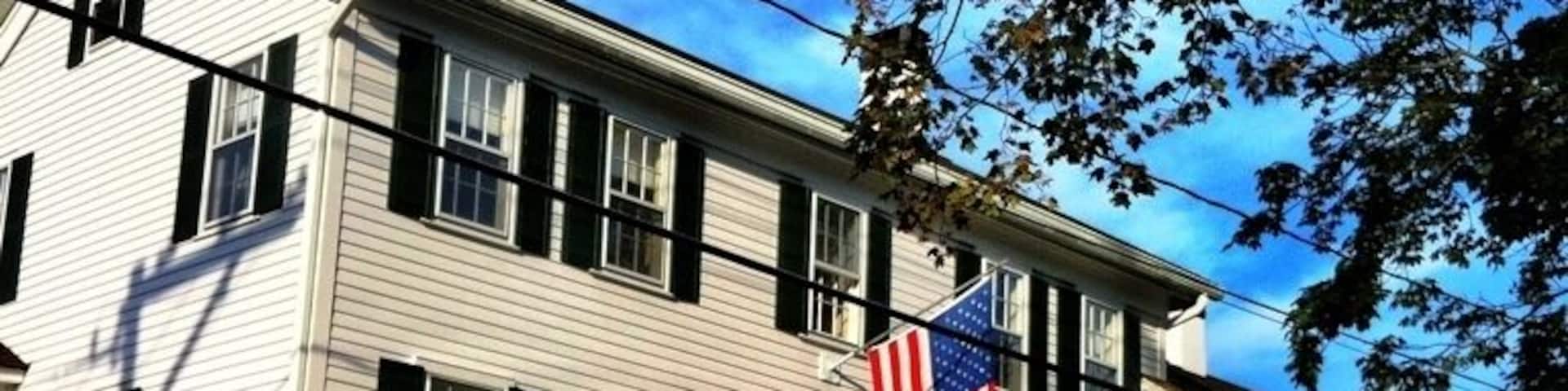 A white building with black shutters, an American flag, and a sign that reads "CHILD'S INN."