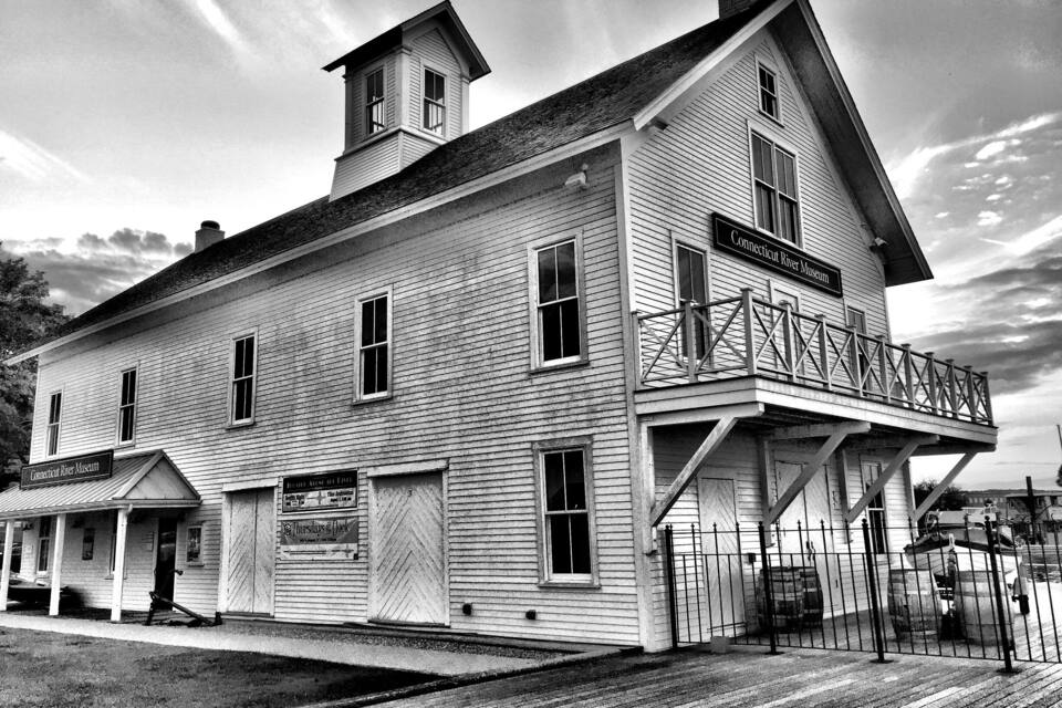 A historic building with a balcony and a sign reading "Connecticut River Museum".