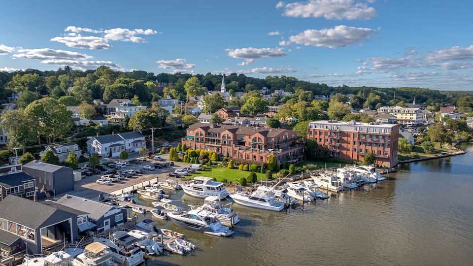 A marina with boats docked, a large brick building, and a church steeple.