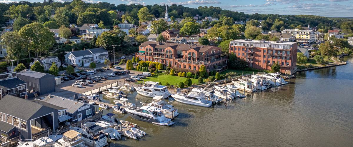 A marina with boats docked, a large brick building, and a church steeple.