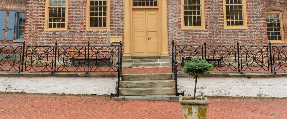 A historic brick building with a yellow door, a balcony, and a red dome.