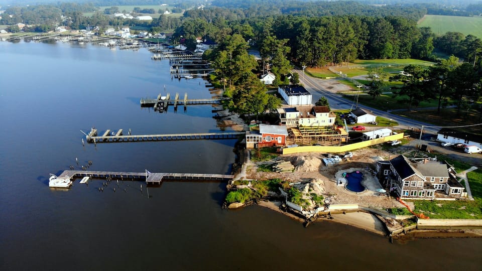 An aerial view of a lakeside town with docks, houses, and a road.