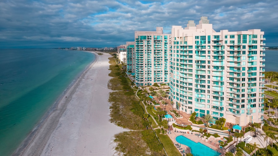 A coastal resort with a beach, a swimming pool, and high-rise buildings.
